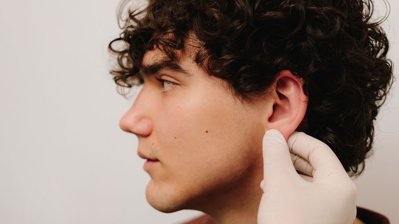 doctor examines ear of male patient before otoplasty surgery